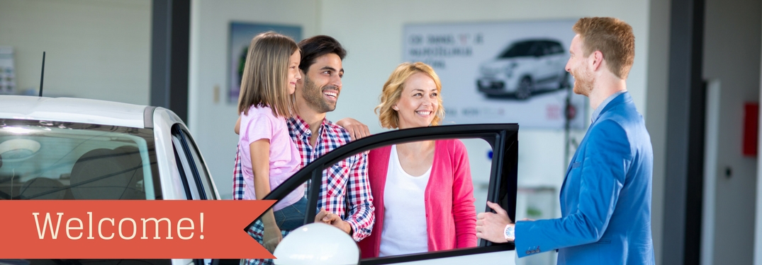 A sales person talking to a family next to a car