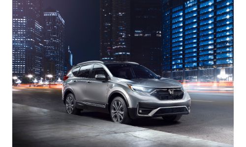 2020 Honda CR-V Touring exterior shot with silver gray paint color parked on the side of a city street at night