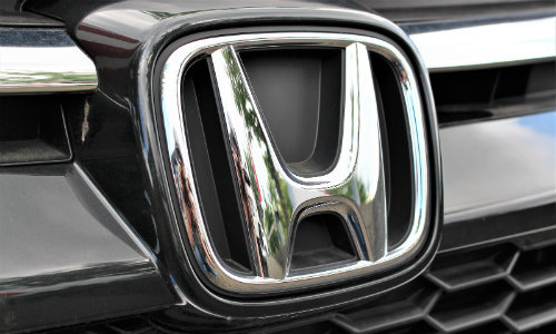 closeup of Honda logo emblem on a car exterior above a mesh grille