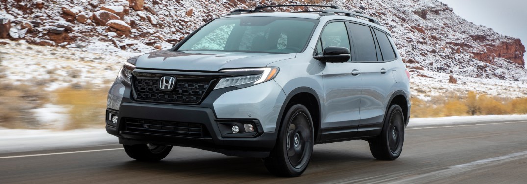 2021 Honda Passport exterior front shot with Lunar Silver Metallic driving on a country highway near snowy mountain cliffs