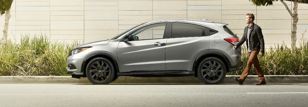 2021 Honda HR-V Sport exterior side shot with Lunar Silver Metallic paint color parked on the side of a road as a man approaches the driver side door