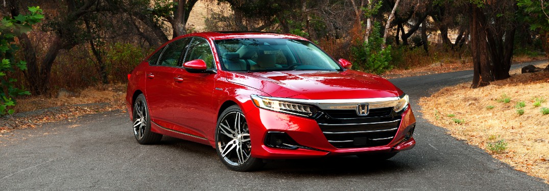 2021 Honda Accord Hybrid exterior shot with red paint color parked on an asphalt road in a forest