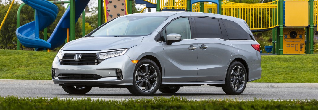 2021 Honda Odyssey exterior shot with Lunar Silver Metallic paint color parked in front of a children's playground park