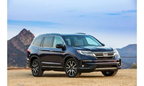 2021 Honda Pilot Elite exterior shot parked on a cliff of yellow dirt with mountains in the background