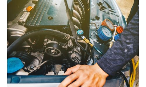 a mechanic waiting for the refrigerant of a vehicle to fully recharge