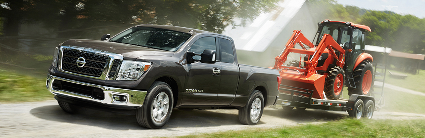 silver nissan titan truck towing a tractor