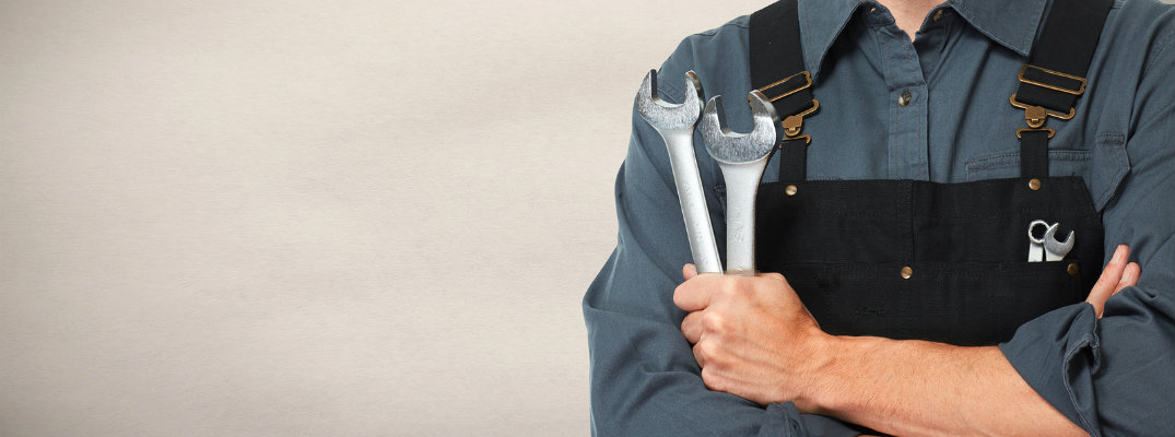 Mechanic holding wrenches in his hands with his arms crossed