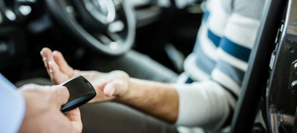 Close up of sales person giving his customer new car keys.