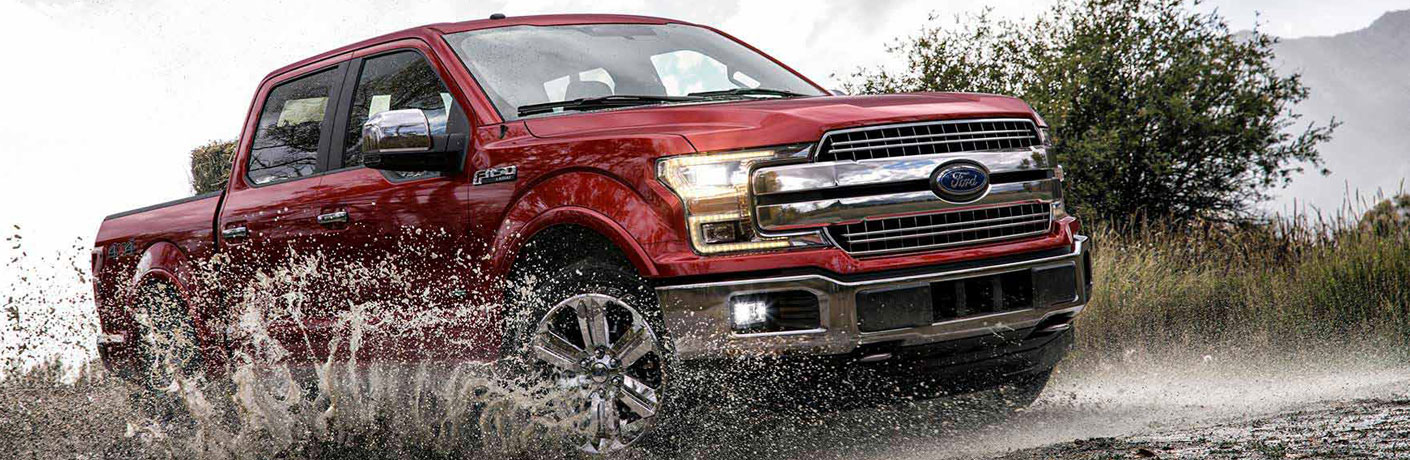 Red Ford F-150 driving through the mud