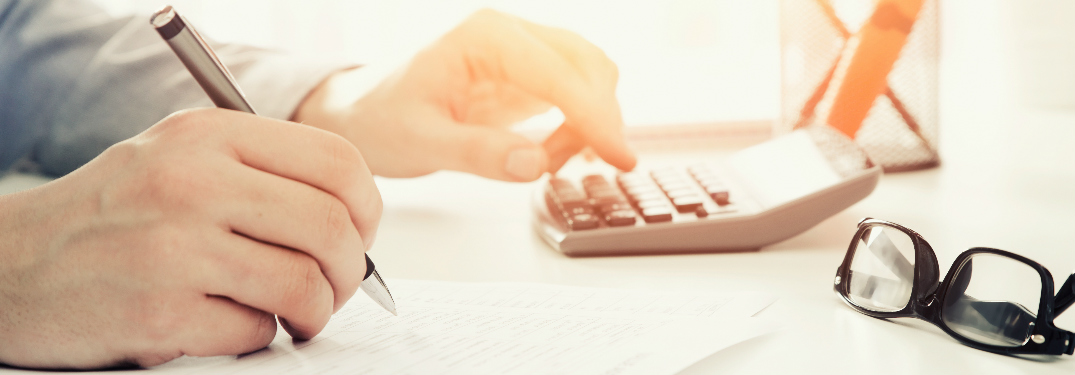 A person using a calculator and filling out a form