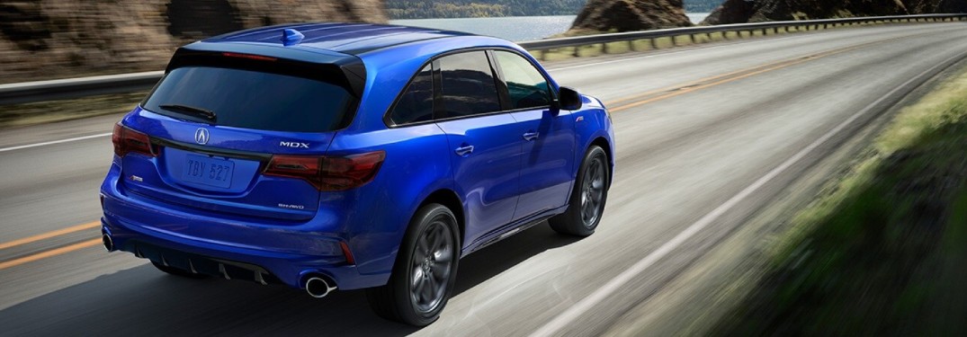 Blue 2020 Acura MDX driving by a mountain lake