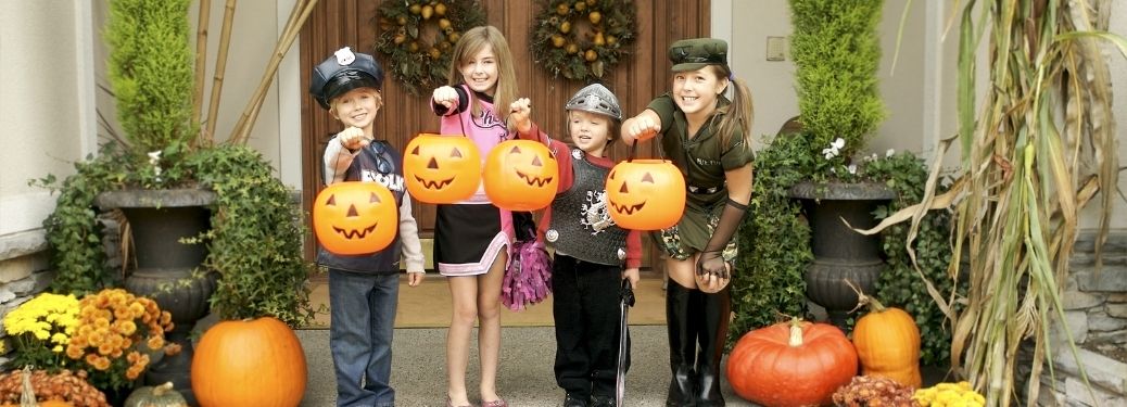 Kids dressed for Halloween standing in front of a house