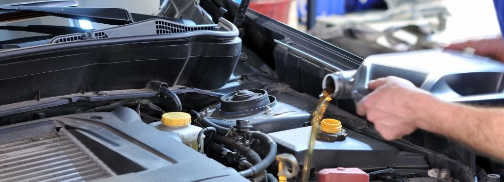 mechanic pouring oil in to the car engine