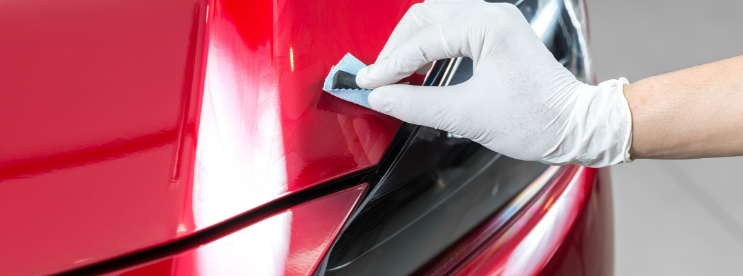 Closeup of hand detailing red vehicle