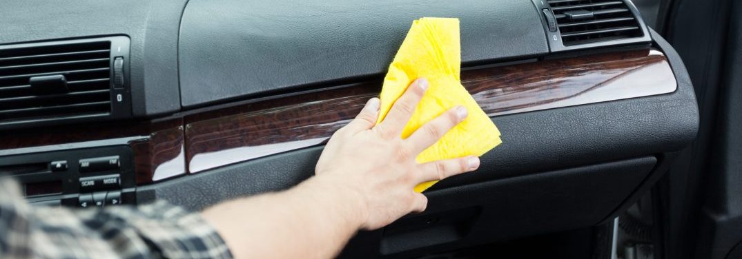 hand with rag wiping down dashboard inside car
