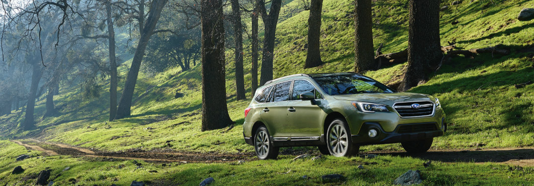 subaru outback driving along a hill on a road