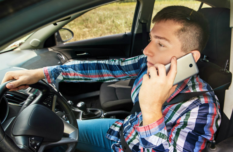 A man driving a car while talking on a phone