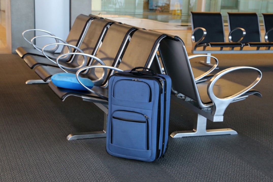 A blue suitcase next to chairs at an airport