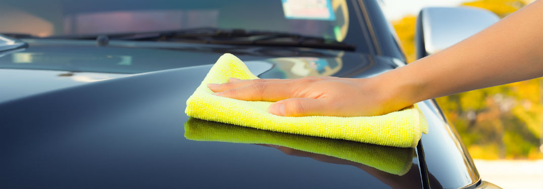 person using microfiber towel to dry off car