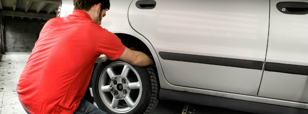 Man in automotive service shop changing a flat tire