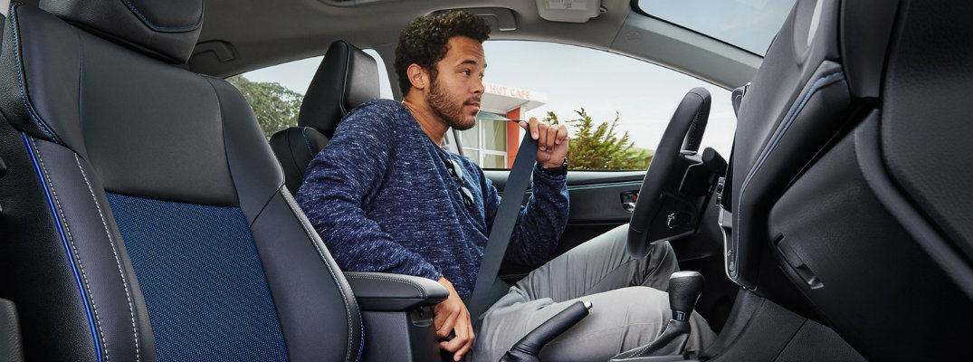 Man buckling up his seat belt inside 2018 Toyota Corolla