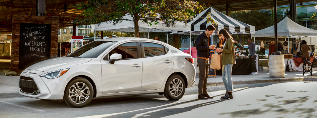 White 2019 Toyota Yaris parked in front of marketplace