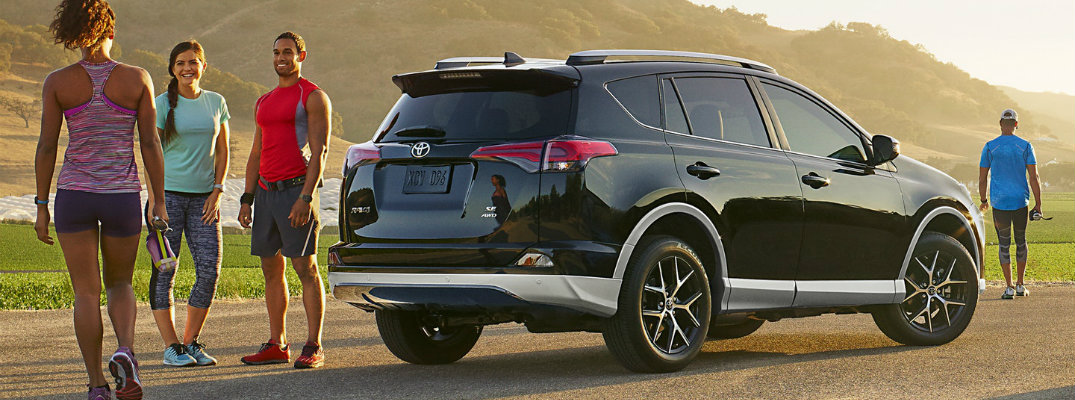 Three athletic people standing next to two-toned 2018 Toyota RAV4