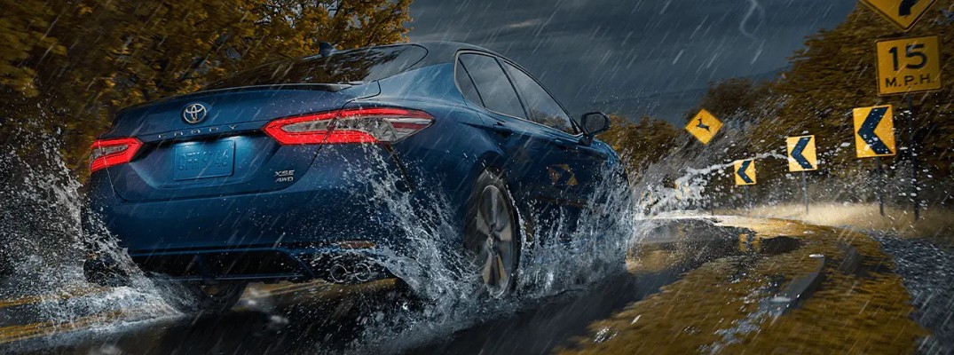 Exterior view of the rear of a 2020 Toyota Camry AWD driving in the rain