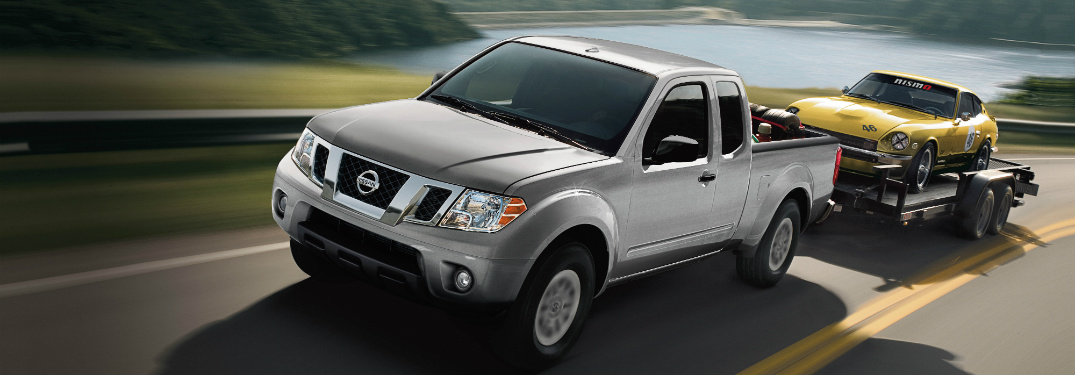 silver 2018 nissan frontier towing trailer with classic yellow sports car