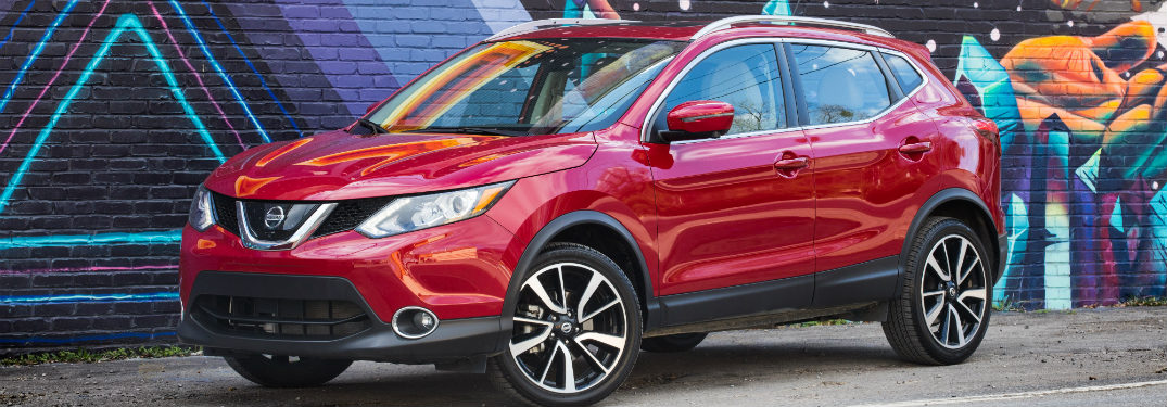 front and side view of red 2018 nissan rogue sport in front of wall mural
