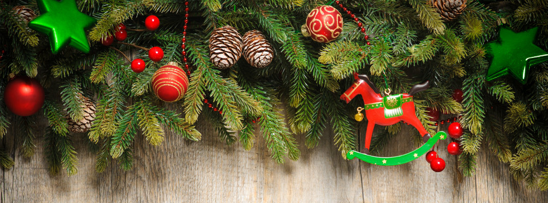 Christmas pine tree wreath line adorned on a wall and decorated with ornaments, bells, and stars
