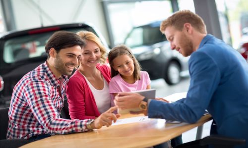 Family discussing a car with a salesman