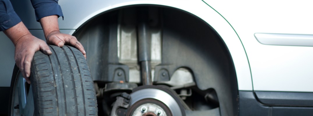 A man next to a car with his hands on a tire