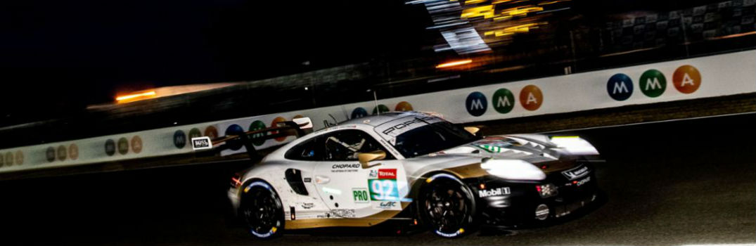 Porsche race car driving on a race track at night