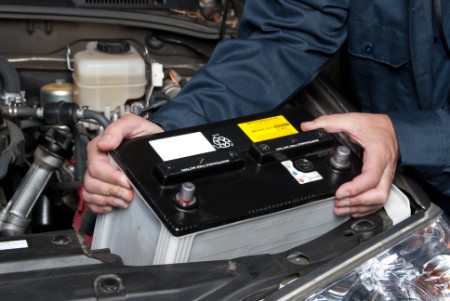 mechanic changing battery of car