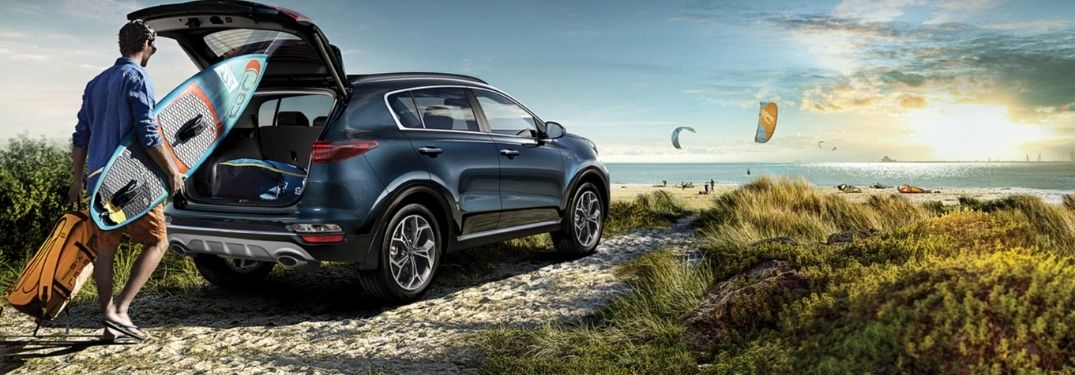 2021 Kia Sportage exterior rear fascia passenger side with man laoding camping gear into open trunk