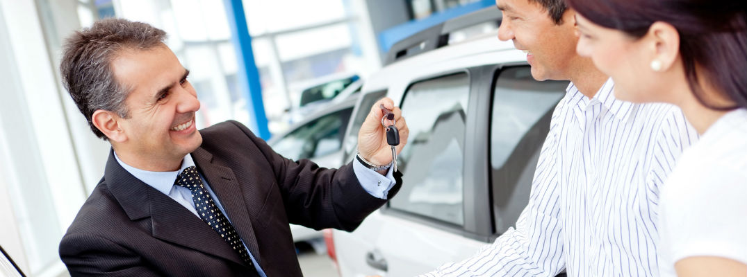 A stock photo of a sales person giving a new set of keys to a customer.