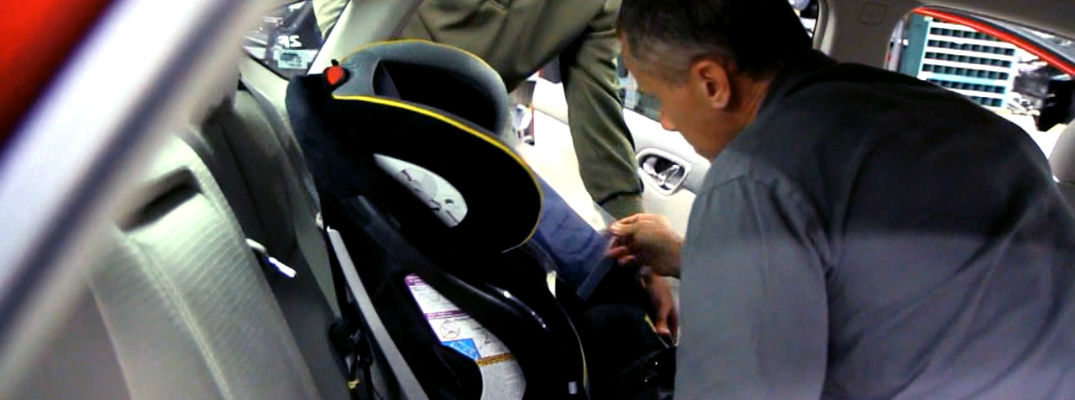 A photo of a person installing a car seat in a Nissan sedan.