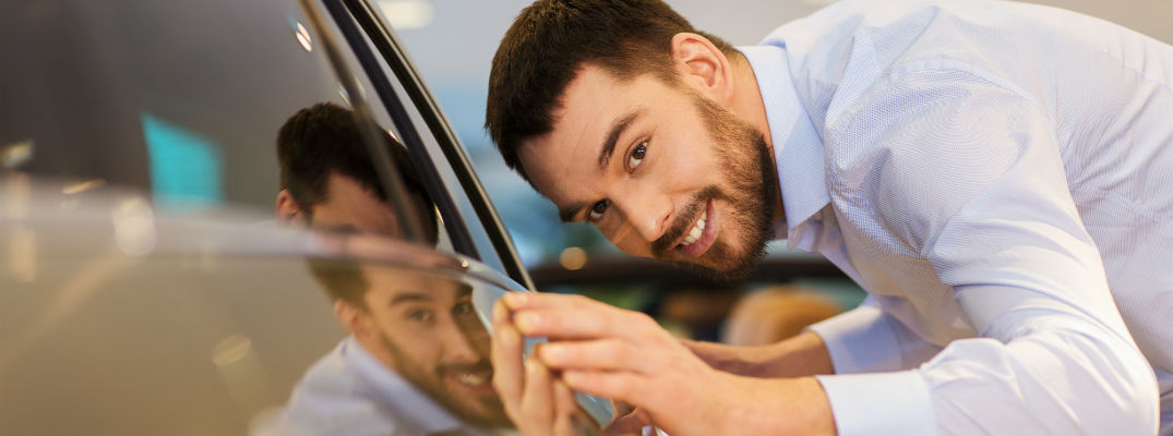 A stock photo of a person looking at a new vehicle.