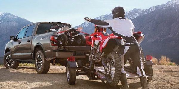 Man Loading a Dirt Bike into the Bed of a 2020 Nissan TITAN
