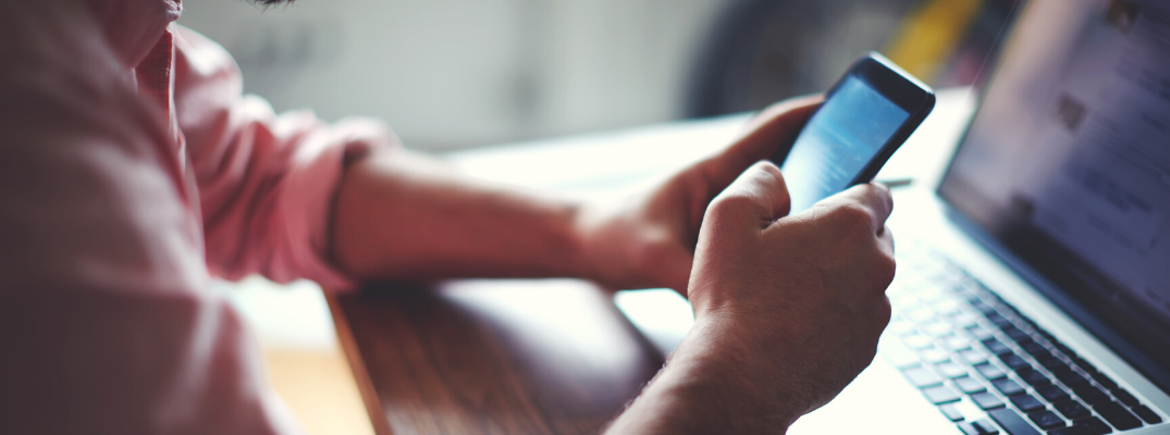 Man sitting at computer and using smartphone