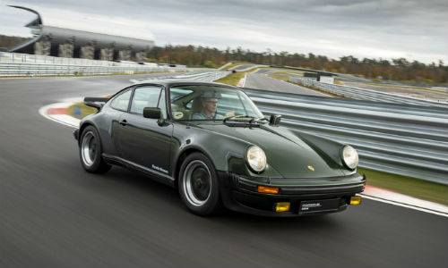 Green historic Porsche 911 model driving on track