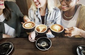 three women laughing and cheering with coffee mugs