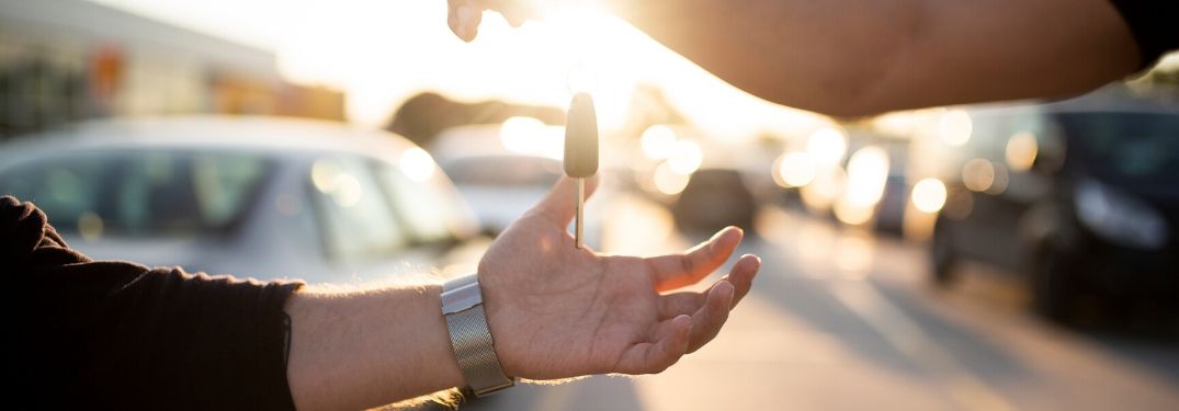 Person dropping key into hand at car dealership