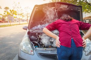 Woman standing in front of overheating car