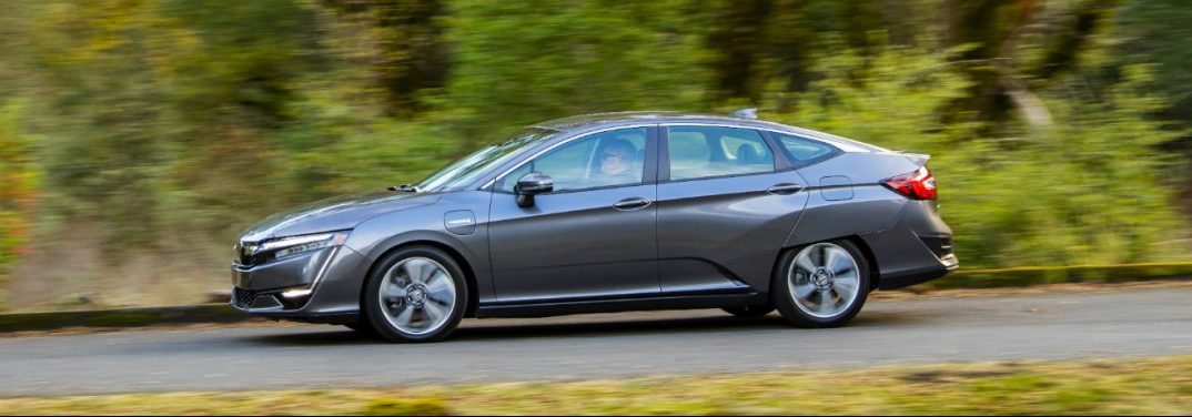 full view of the 2018 Honda Clarity Plug-In Hybrid driving on a country road