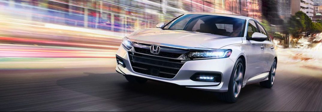 White 2020 Honda Accord drives at high speed up a city street.