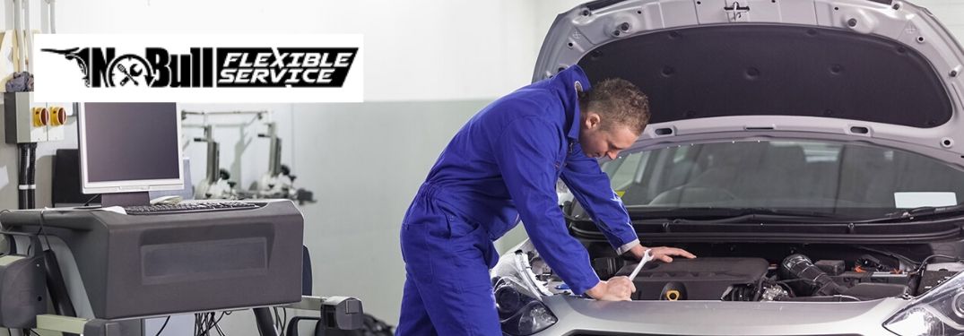 Mechanic Working Under the Hood of a Car with Black No Bull Flexible Service Logo in Upper Left Corner