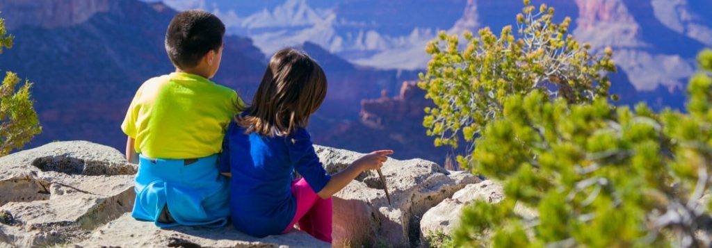 Kids Sitting on a Rock in a Desert Overlooking a Valley