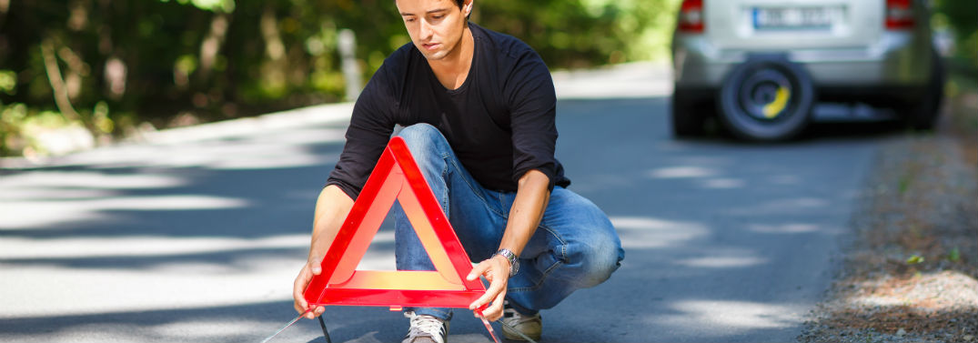 How to Make a Roadside Emergency Kit with image of a guy putting a triangle reflector on the road behind his car